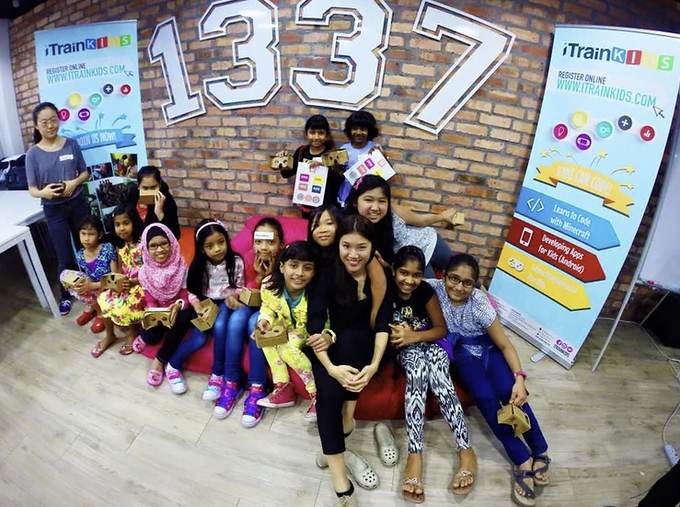 Raeesa Sya with a group of young girls holding cardboard viewers at an iTrain Kids coding session.