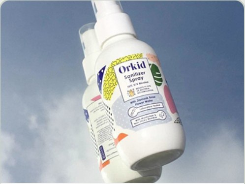 Orkid sanitiser spray bottles against a sky background.